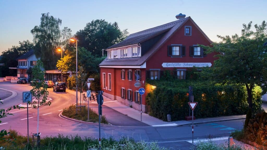 Das Restaurant Papageno bei Abenddämmerung. Zu sehen ist ein altes Haus mit rotem Gemäuer.